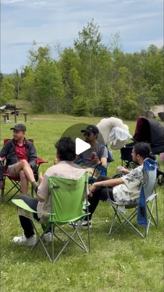 People sitting together in camp chairs on the grass at the community picnic.